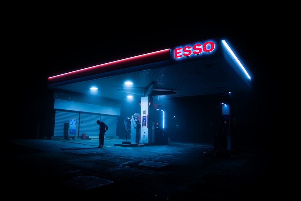 a man standing in front of a gas station at night