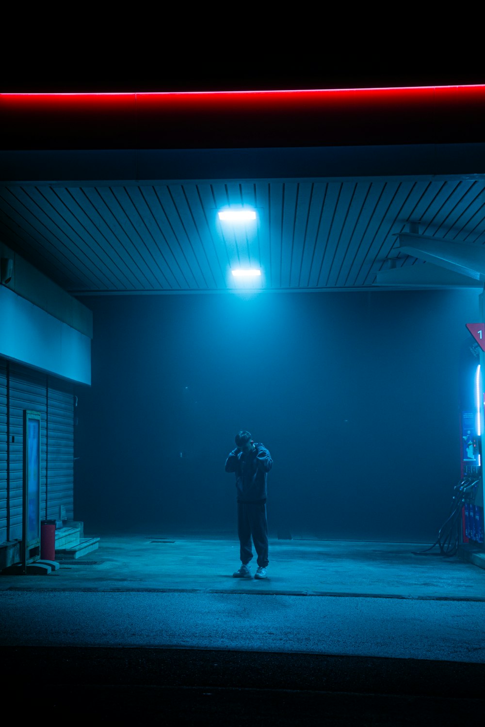 a man standing in a gas station at night