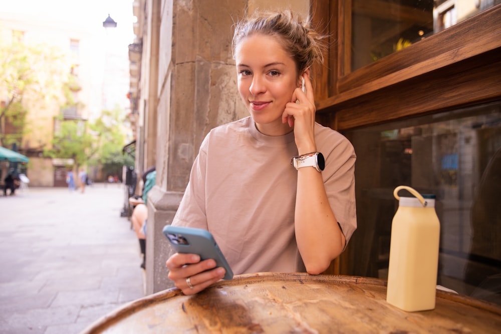 a woman sitting at a table using a cell phone