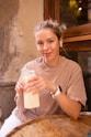 a woman sitting at a table holding a bottle of milk