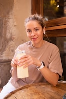 a woman sitting at a table holding a bottle of milk