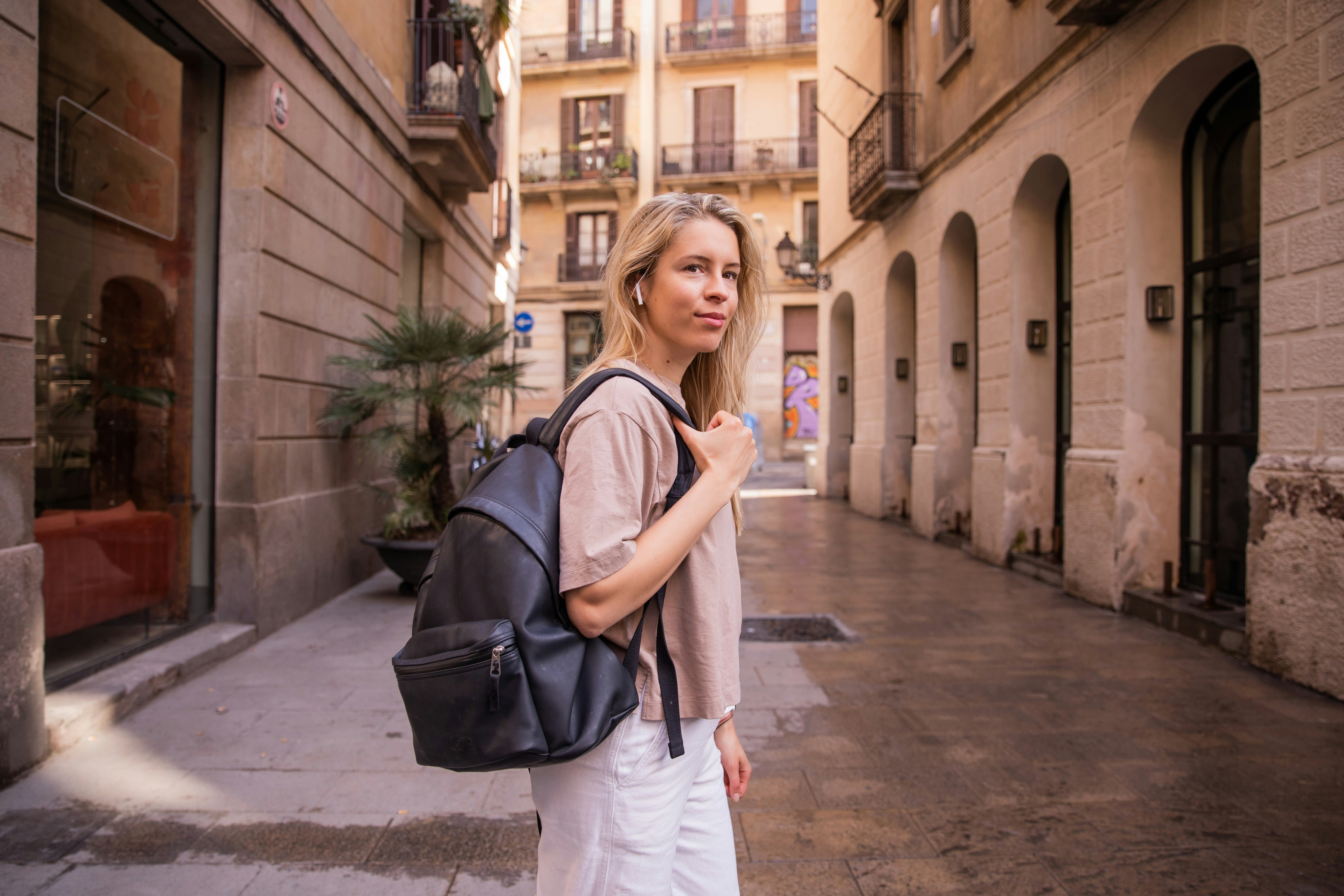a woman with a backpack is walking down the street
