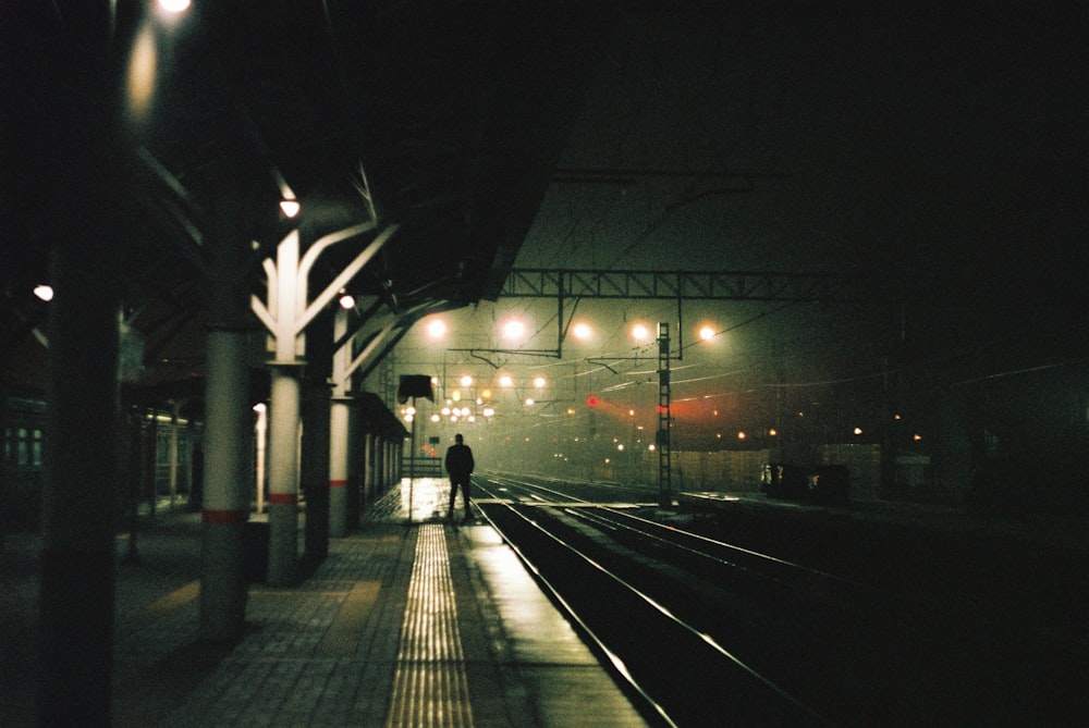 a person standing on a train platform at night