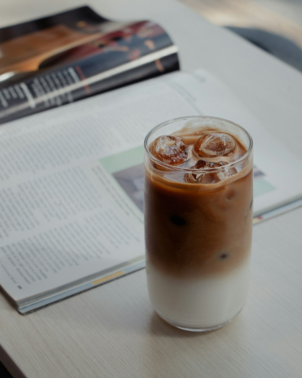 a glass of iced coffee sitting on top of a table