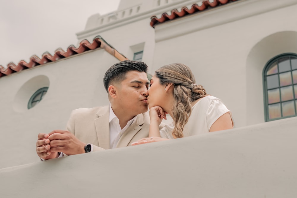 a man and woman kissing each other in front of a building