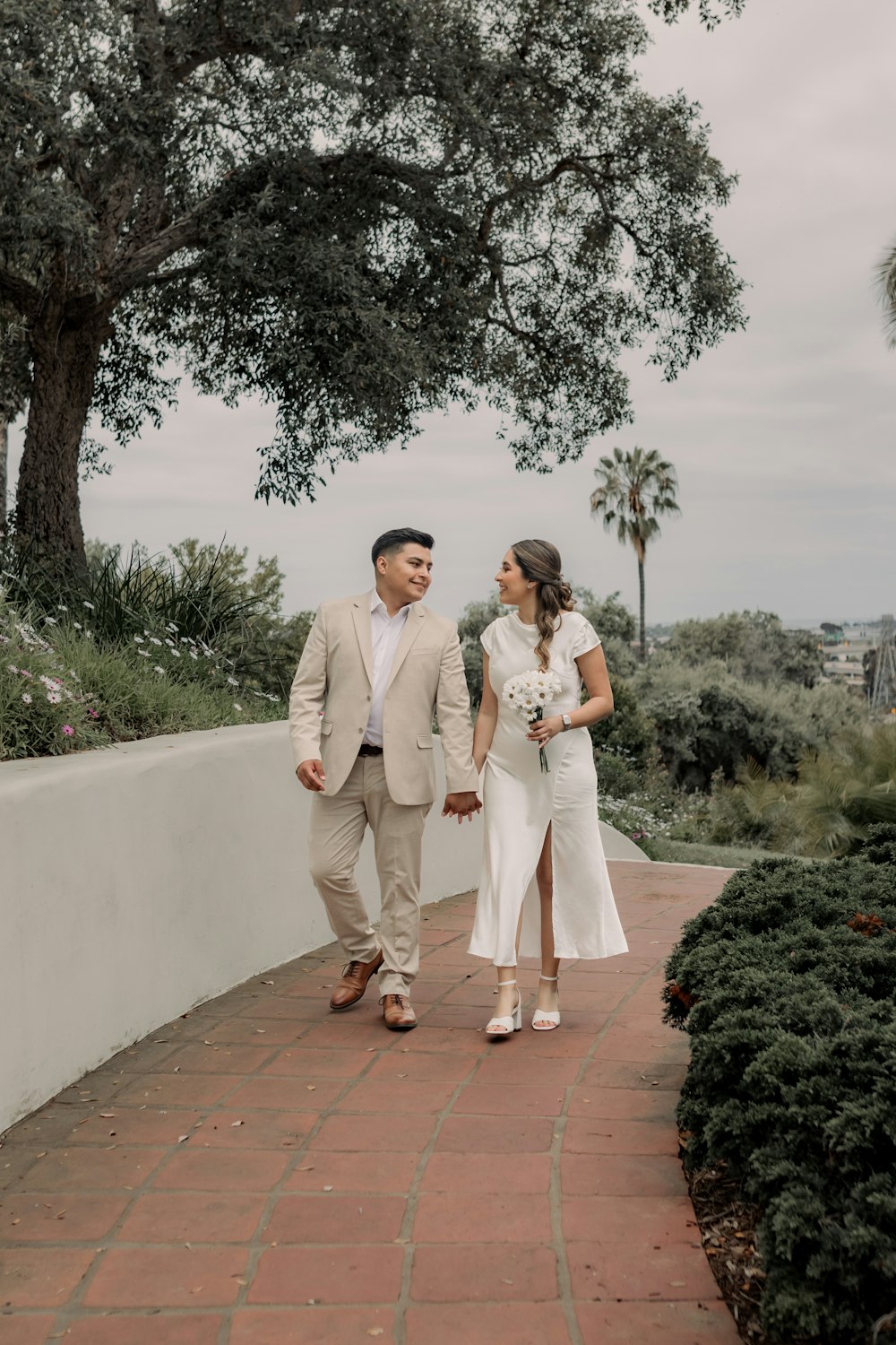 a bride and groom walking down a brick path