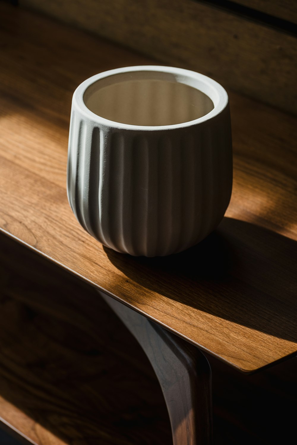 a white vase sitting on top of a wooden table