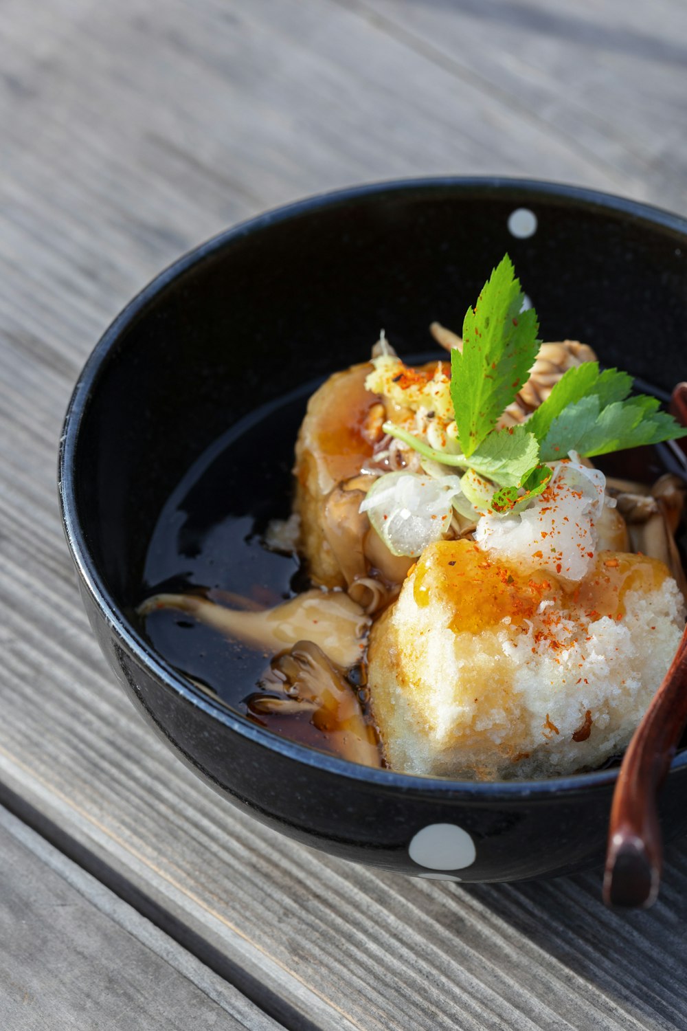 a black bowl filled with food on top of a wooden table