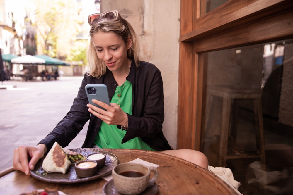 a woman sitting at a table looking at her phone