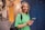 a woman in a green shirt holding a cell phone