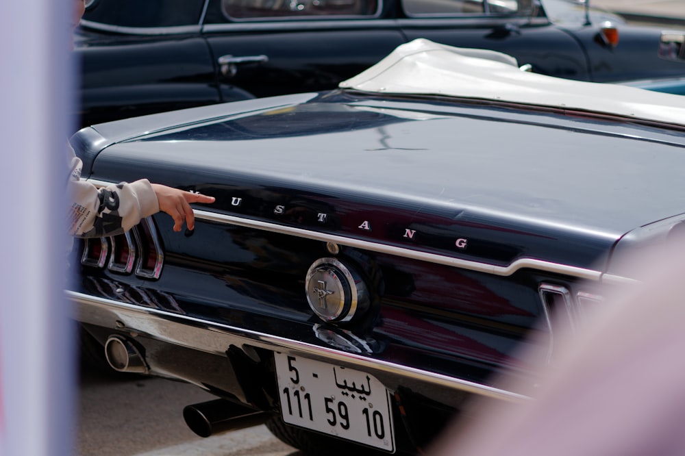 a woman points at a car parked in a parking lot