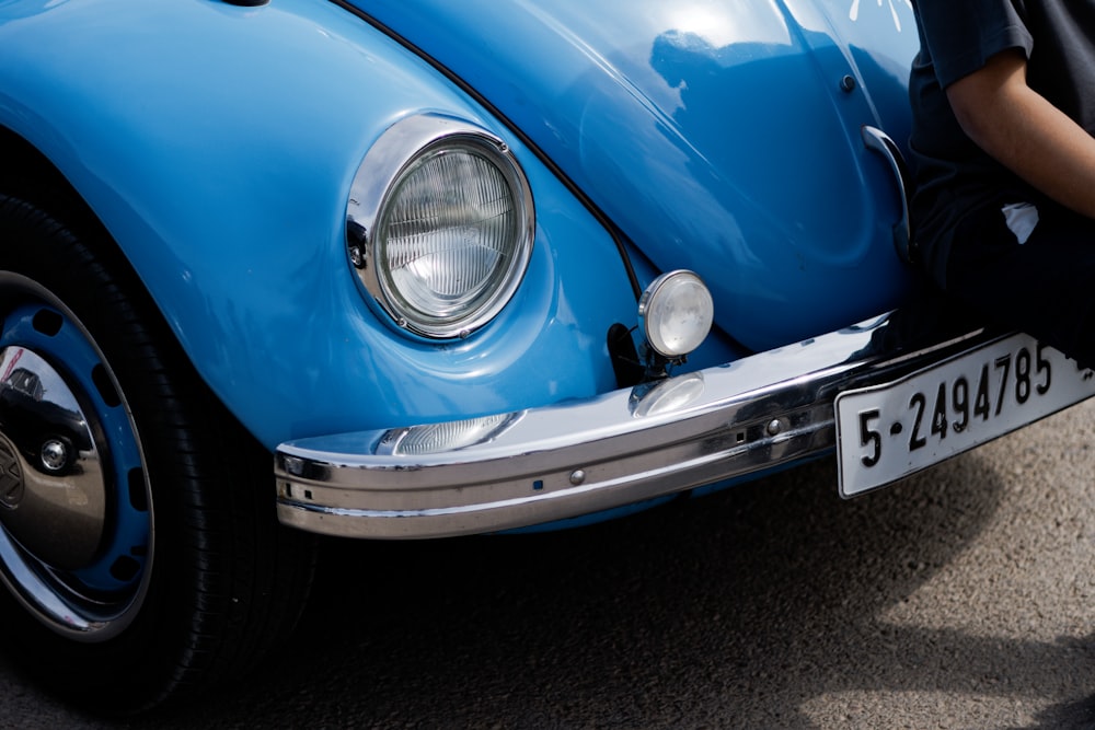 a person sitting on the front of a blue car