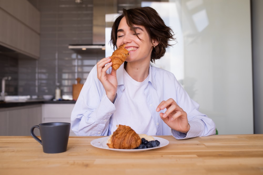 a woman sitting at a table eating a pastry