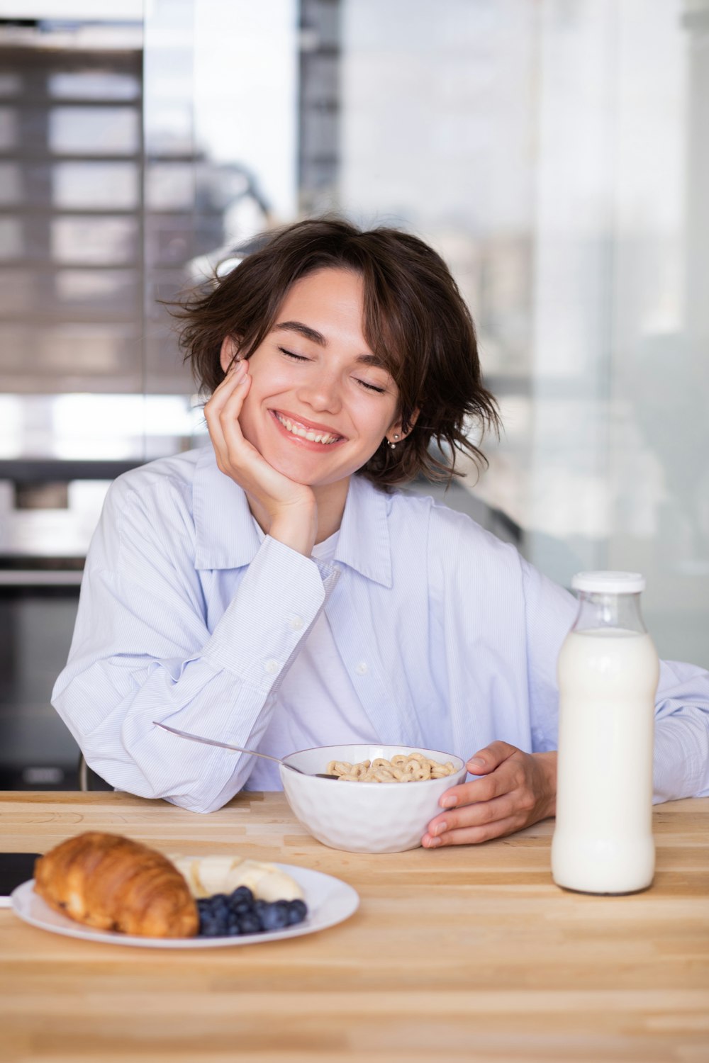 a woman sitting at a table with a bowl of cereal