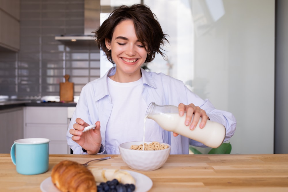 a woman pouring milk into a bowl of cereal