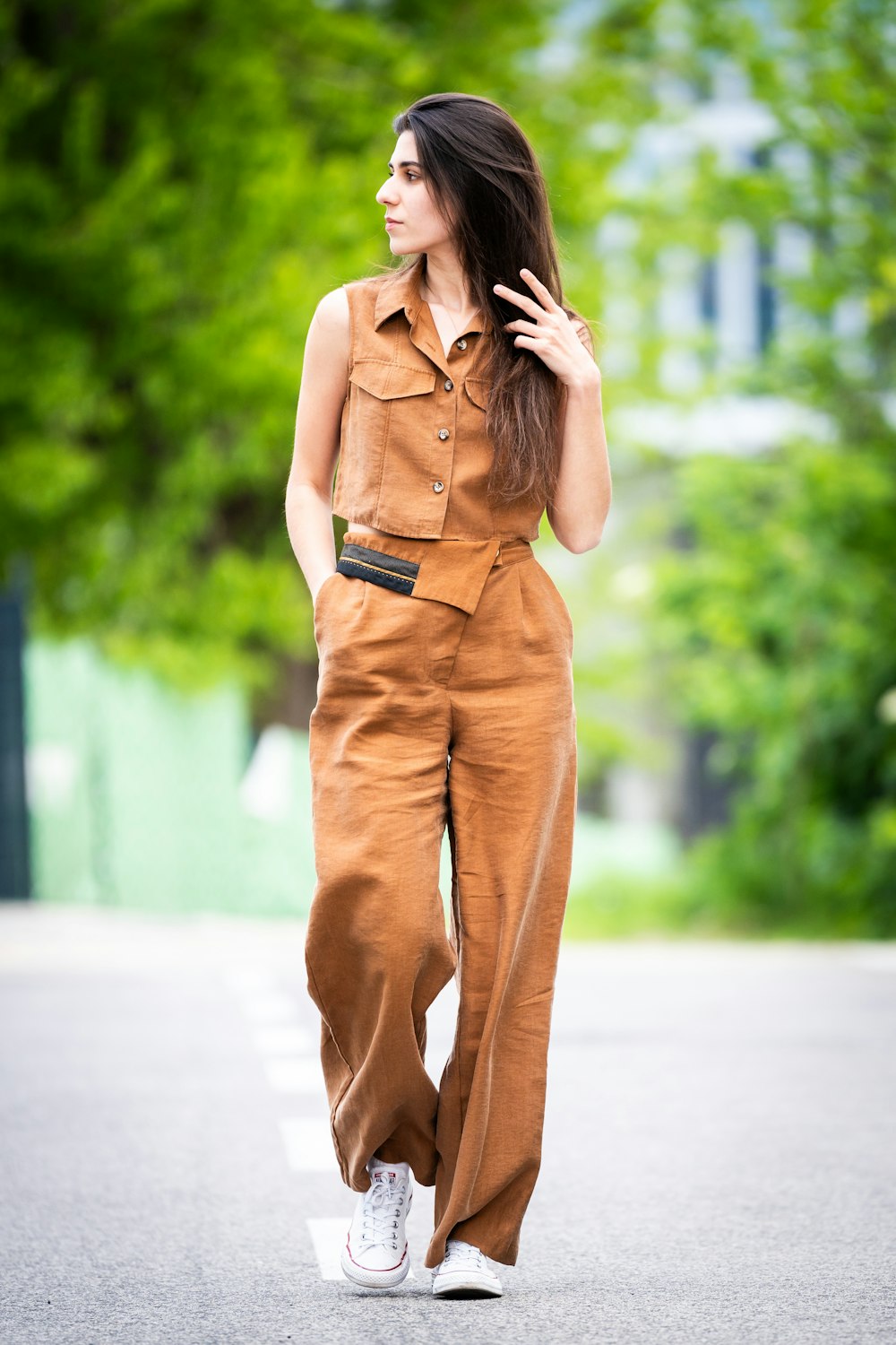 a woman in a brown jumpsuit is walking down the street