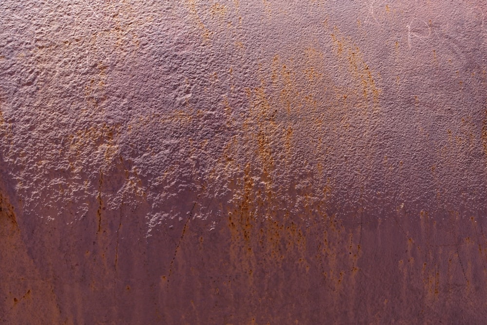 a rusted metal surface with yellow paint on it