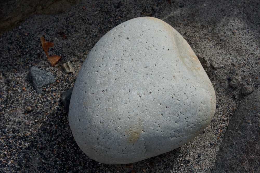 ein weißer Felsen, der auf einem Sandstrand sitzt