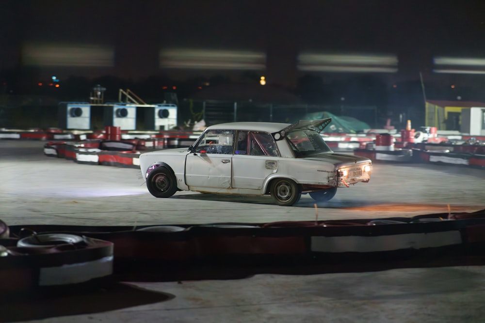 a white car driving down a street at night