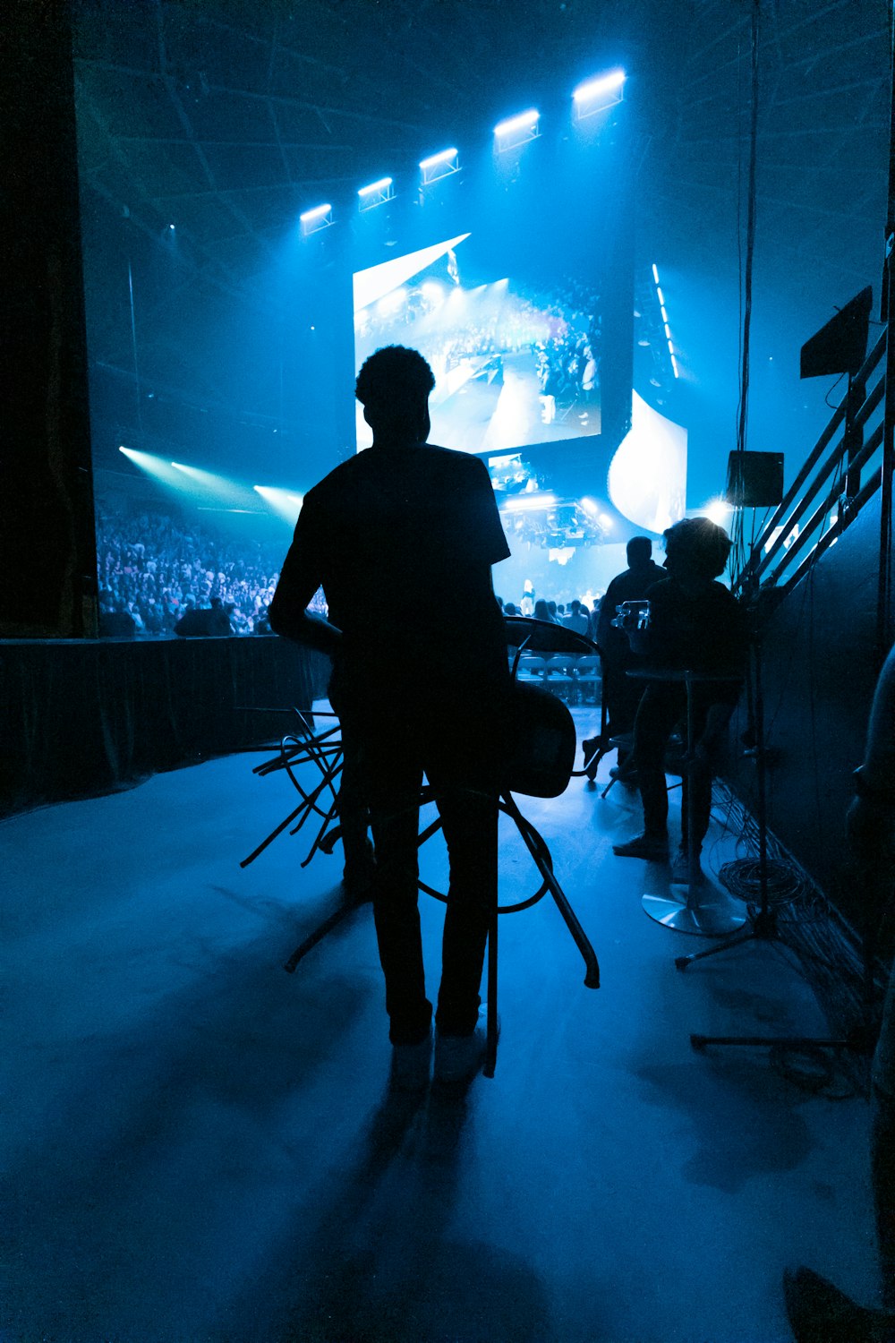 Un hombre parado frente a un escenario con una guitarra