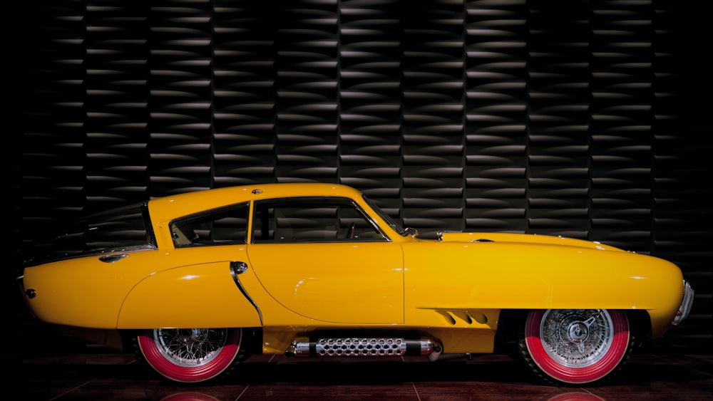 a yellow car parked in front of a wall