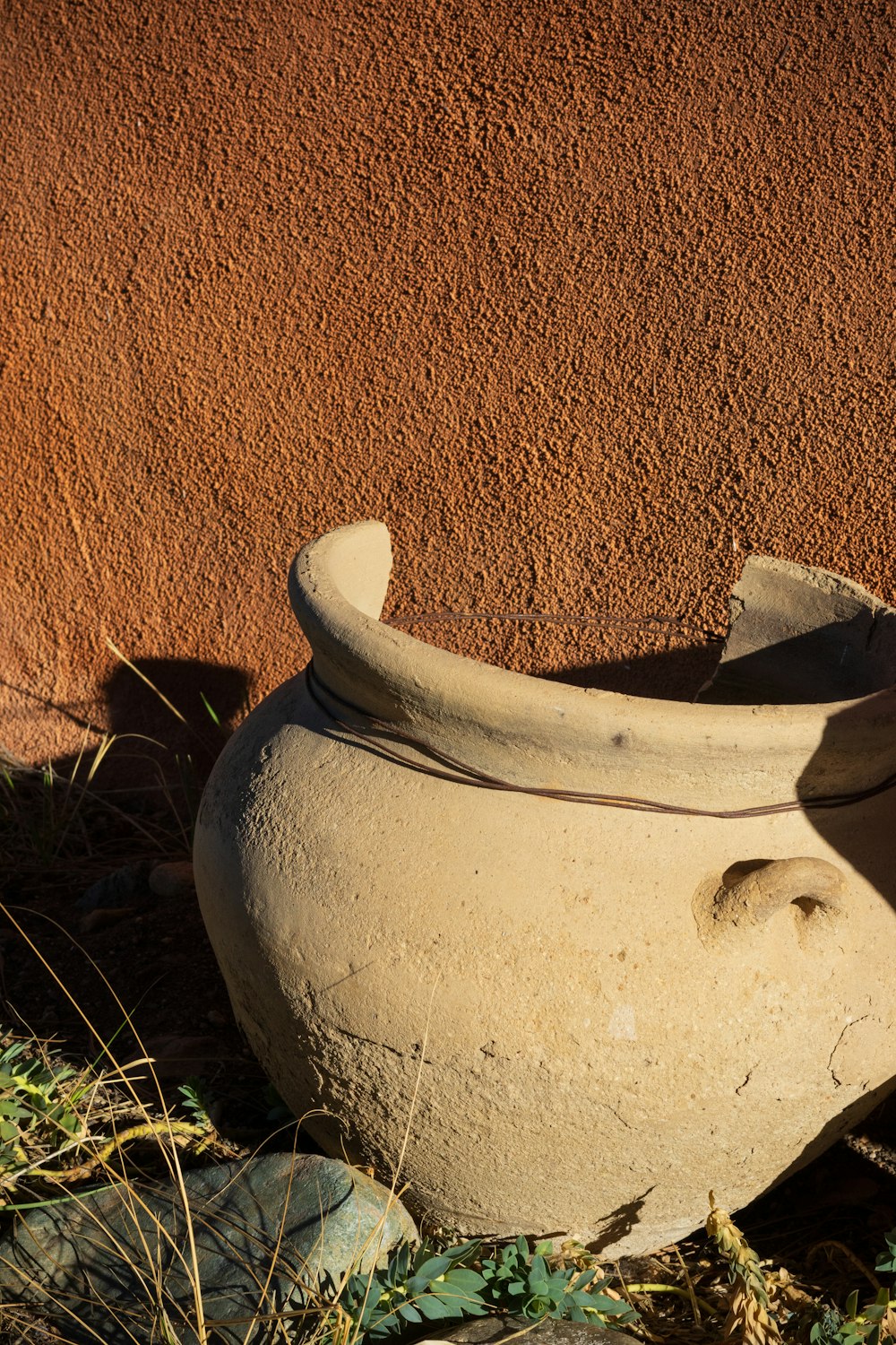 a clay pot sitting on the ground next to a wall