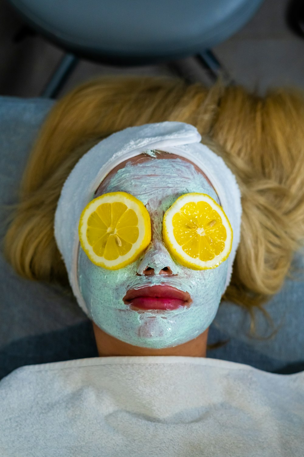 a woman with a towel on her head and two slices of lemon on her face