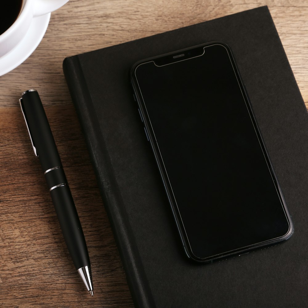 a notepad, pen, and cell phone on a desk