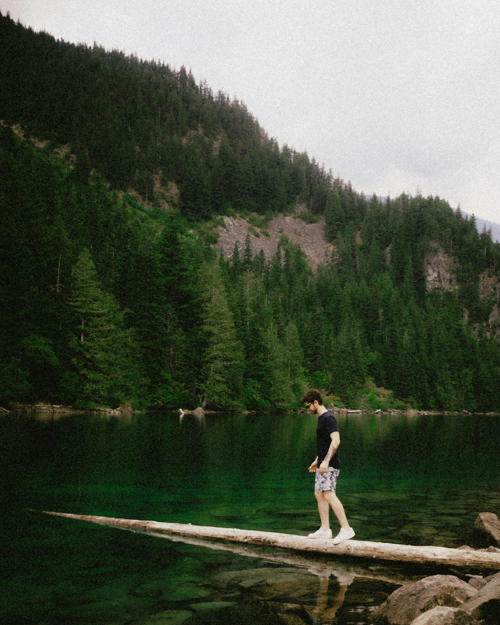 a man standing on a log in the middle of a lake