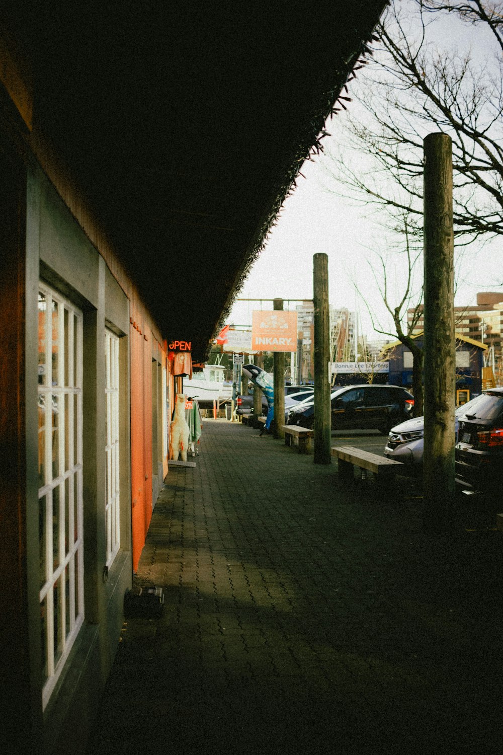 a sidewalk with a row of parked cars next to a building