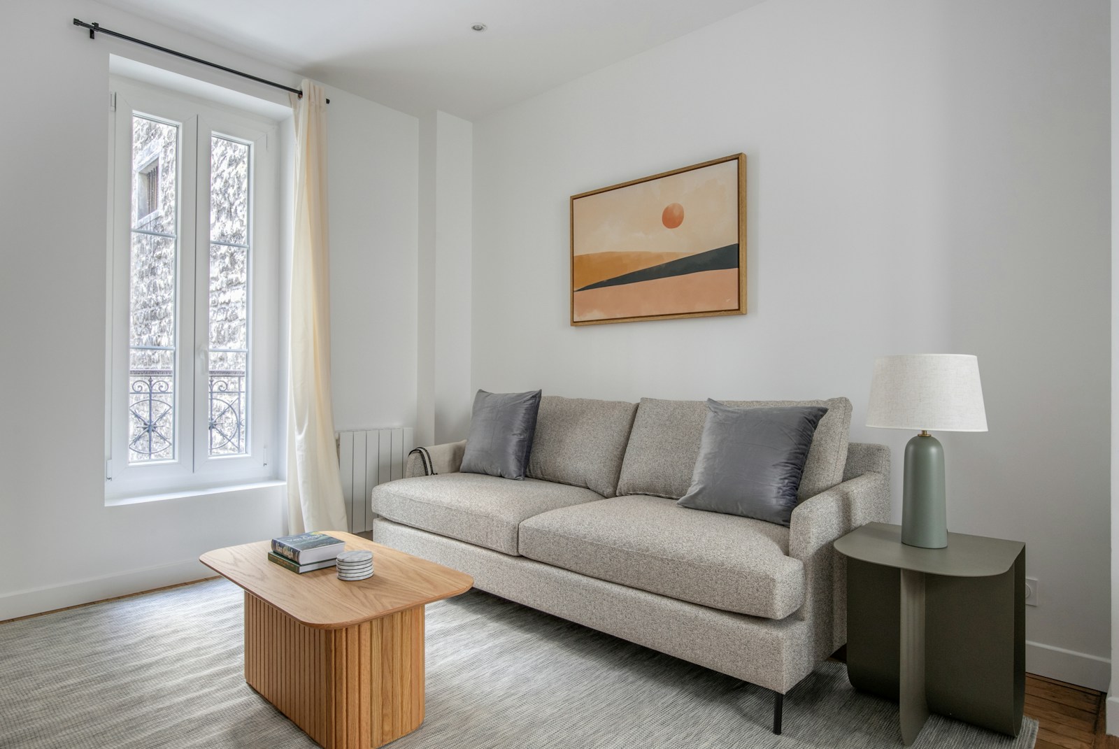 styled small apartment living room with sunset art neutral sofa lamp and rug