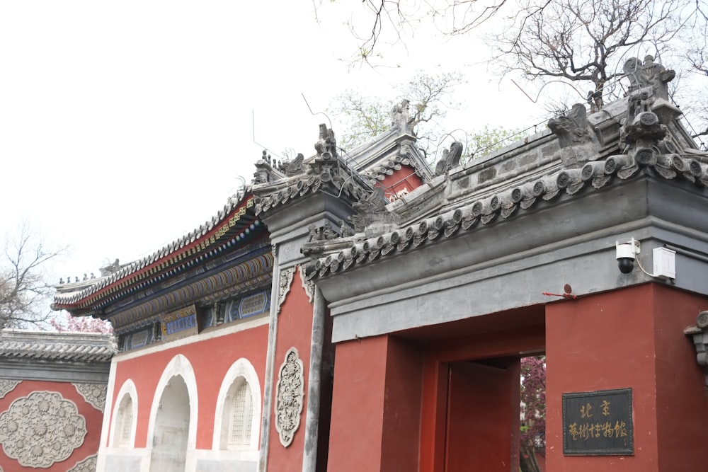 a building with a red wall and a tree in front of it