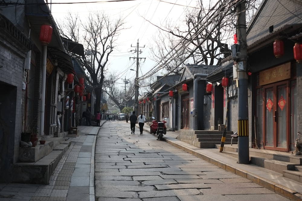 a couple of people walking down a street next to buildings