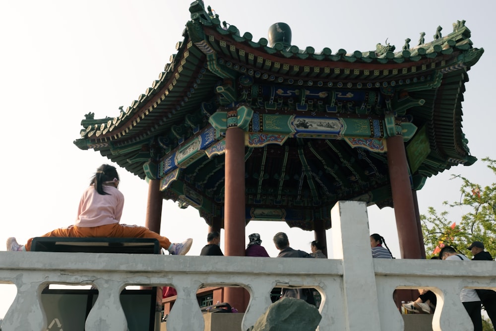 a woman sitting on a bench in front of a pagoda