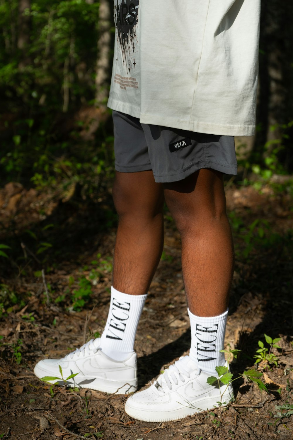 a person standing in the woods wearing white shoes