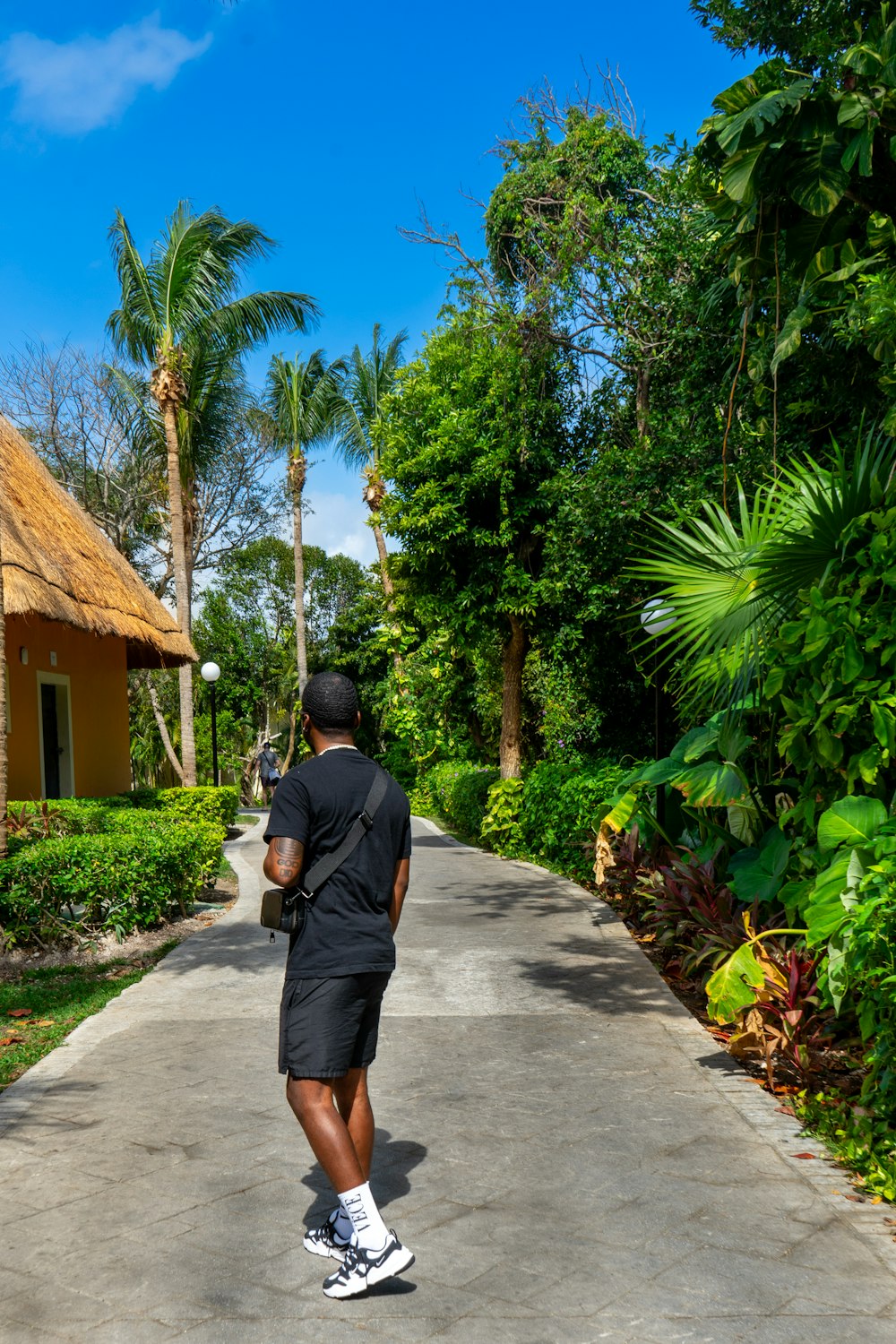 a man walking down a street next to a lush green forest