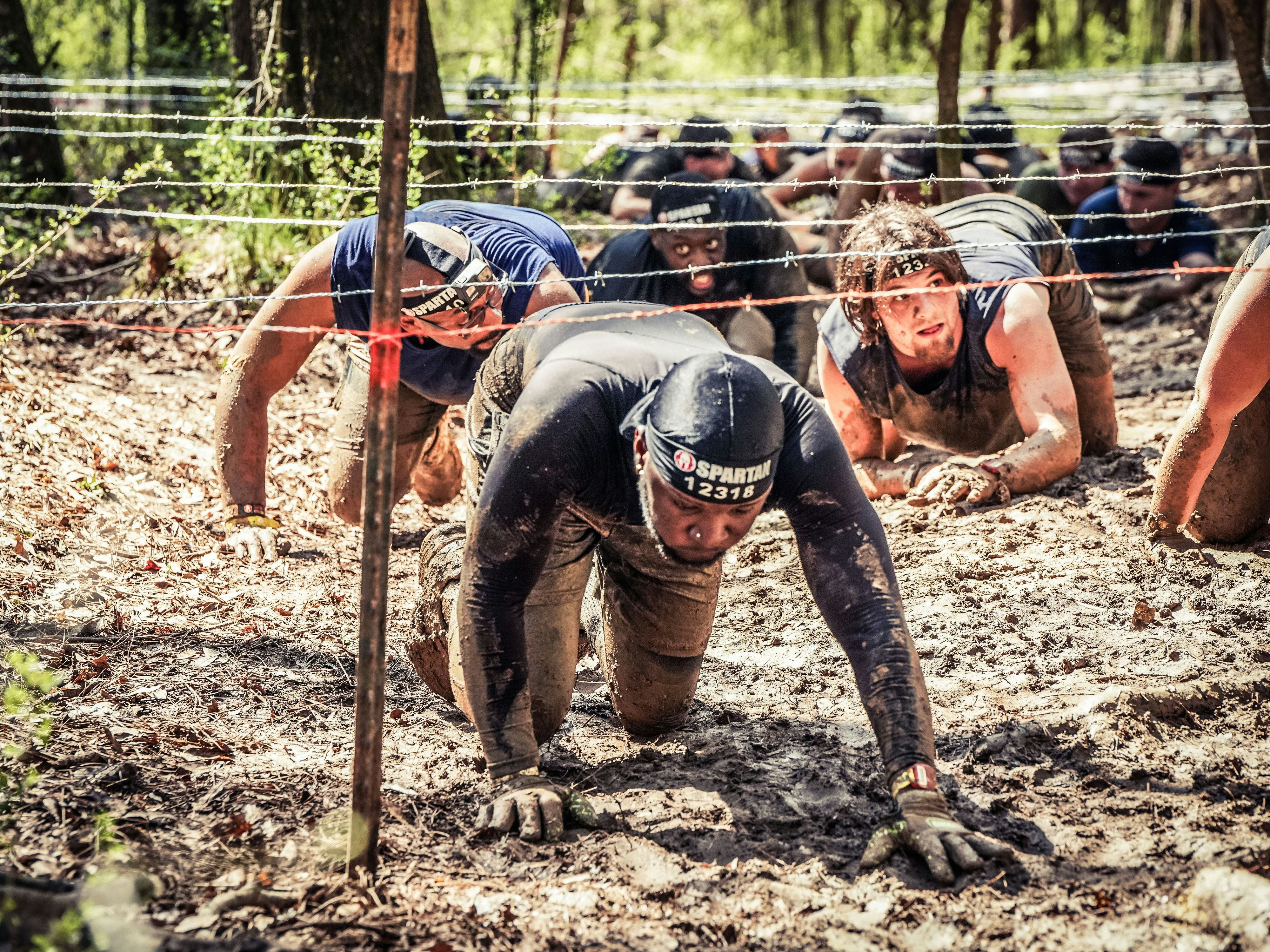 a group of men in mud suits climbing up a hill