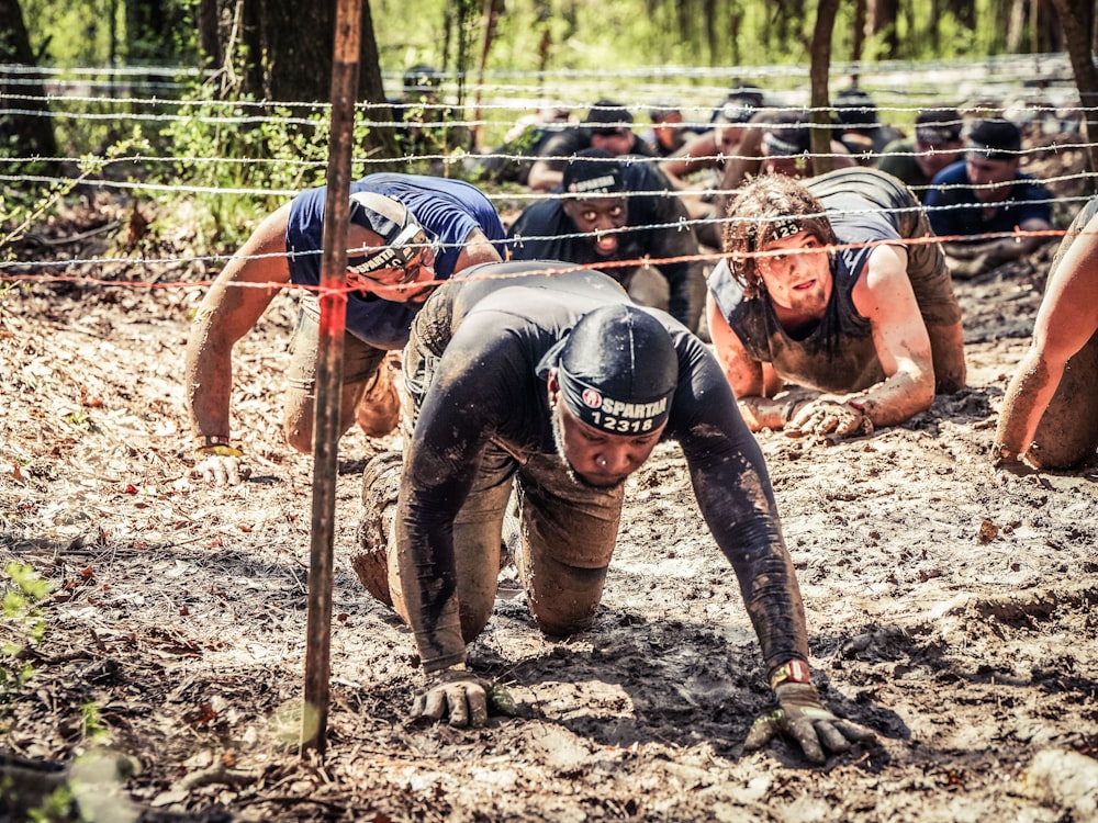 a group of men in mud suits climbing up a hill