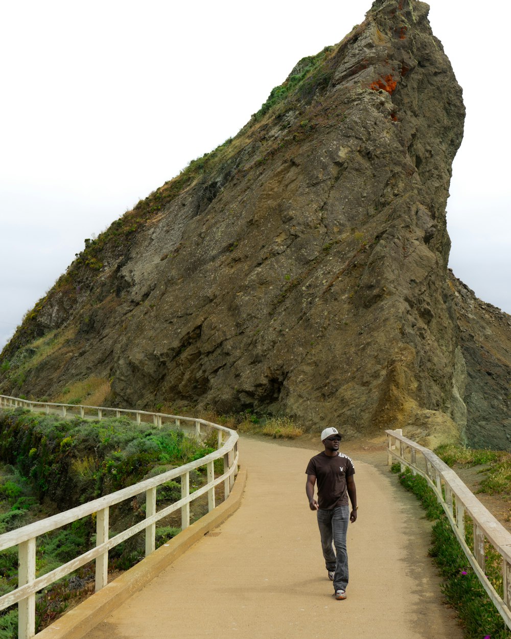 a man walking down a path towards a large rock