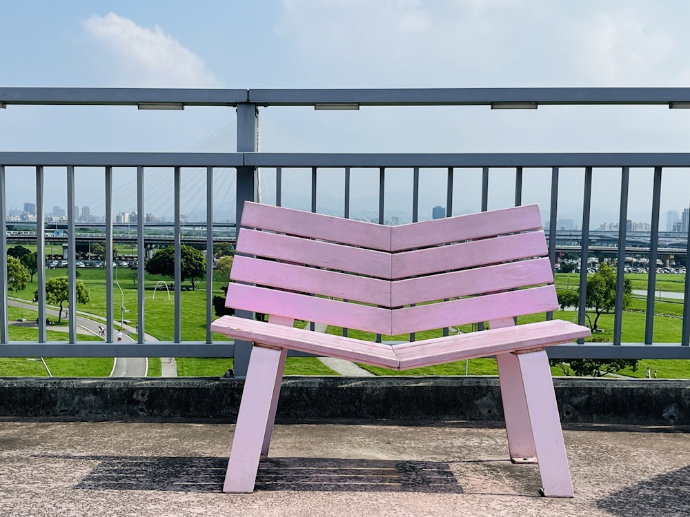 a pink bench sitting on top of a sidewalk