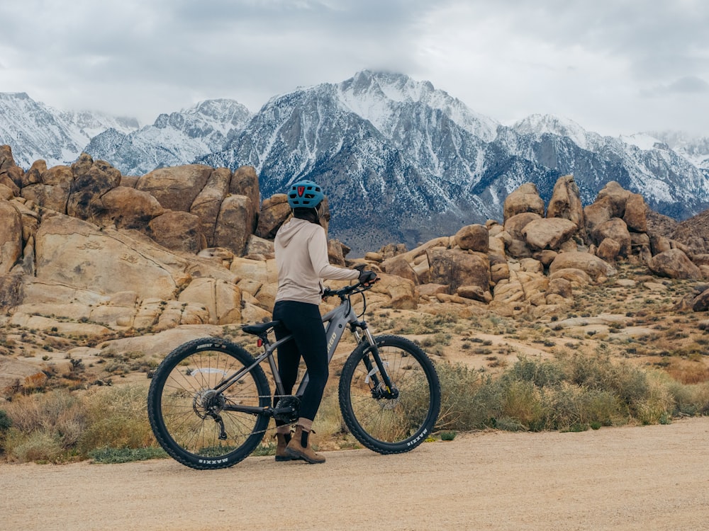 a person standing next to a bike on a dirt road