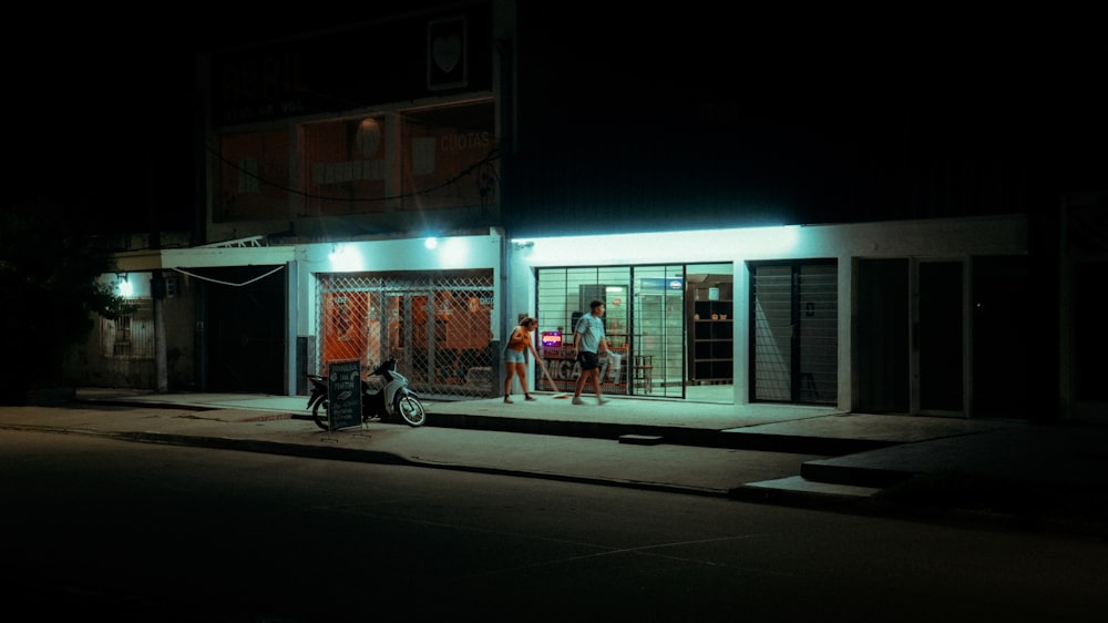 a man standing outside of a store at night