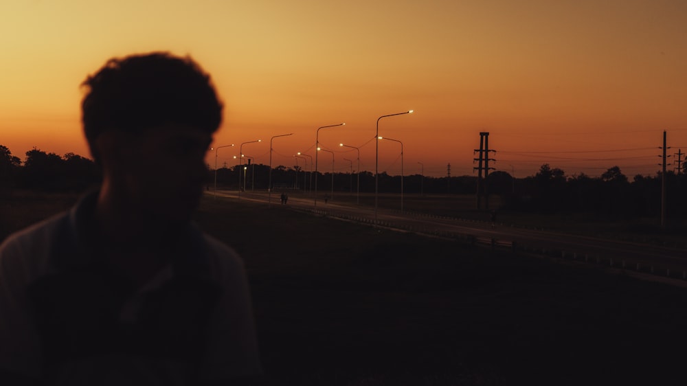 a man standing in the middle of a road at sunset