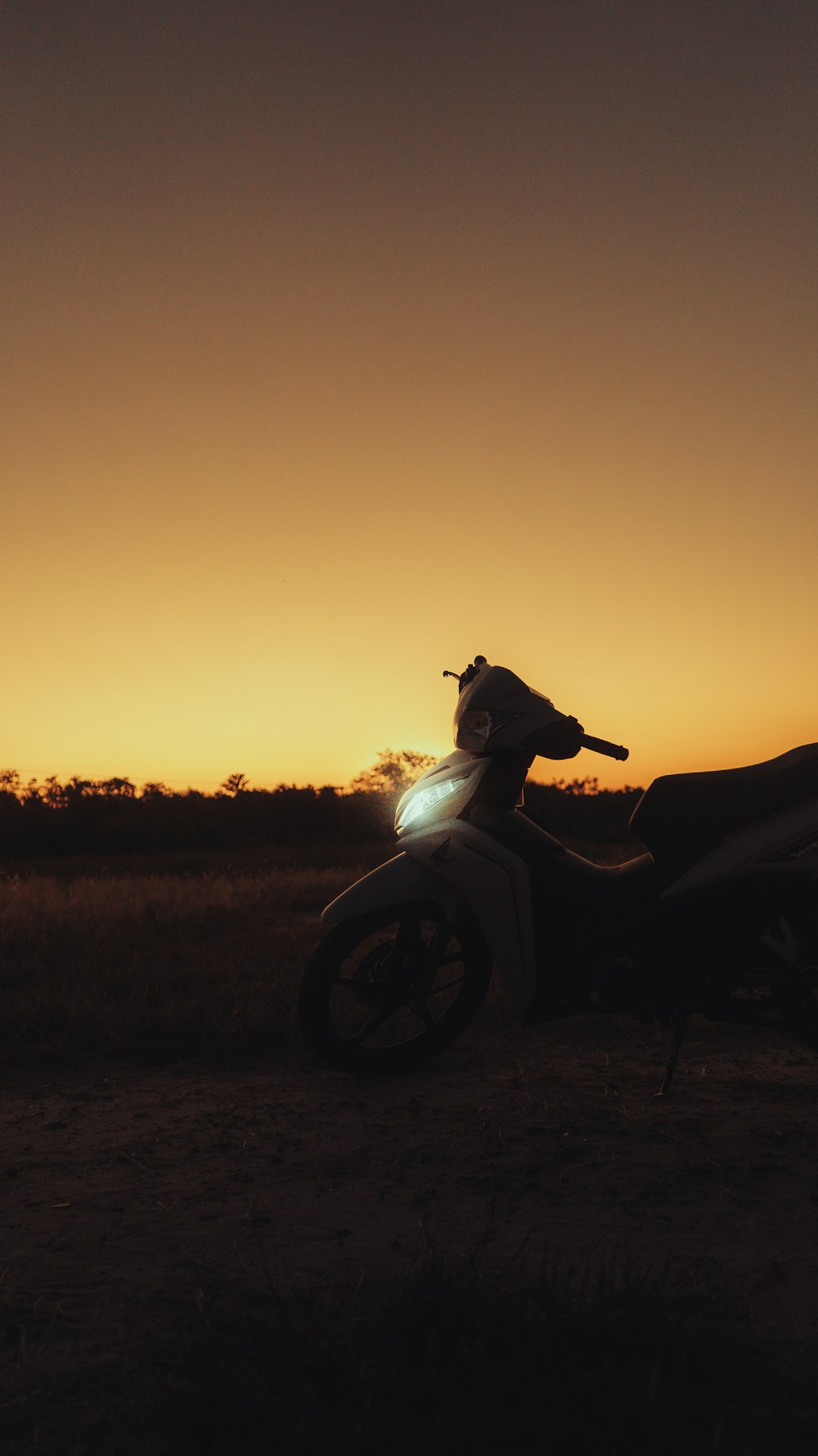 a motorcycle parked in a field at sunset