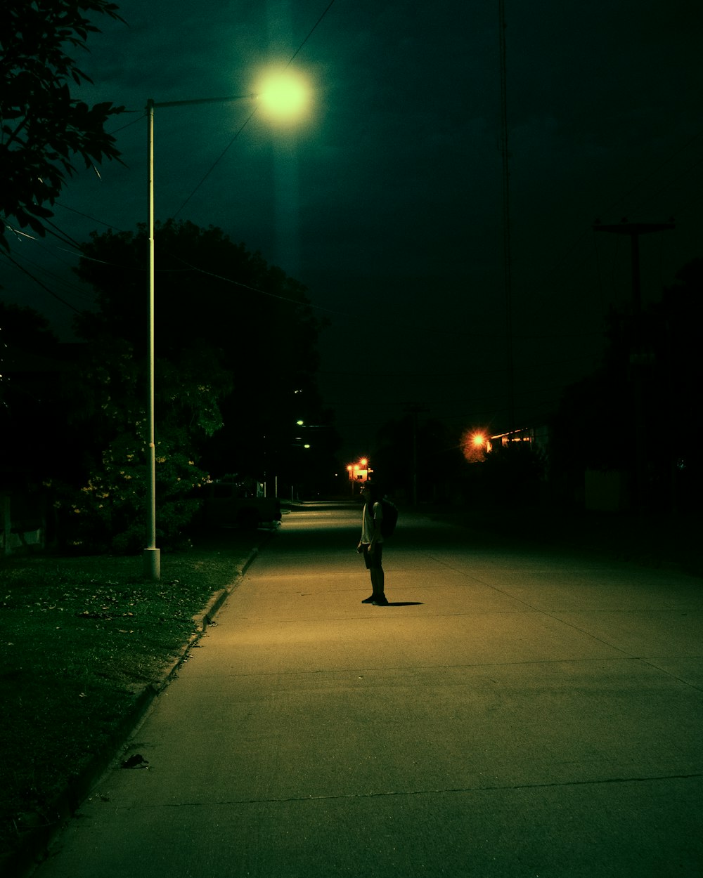 a person standing on a sidewalk at night