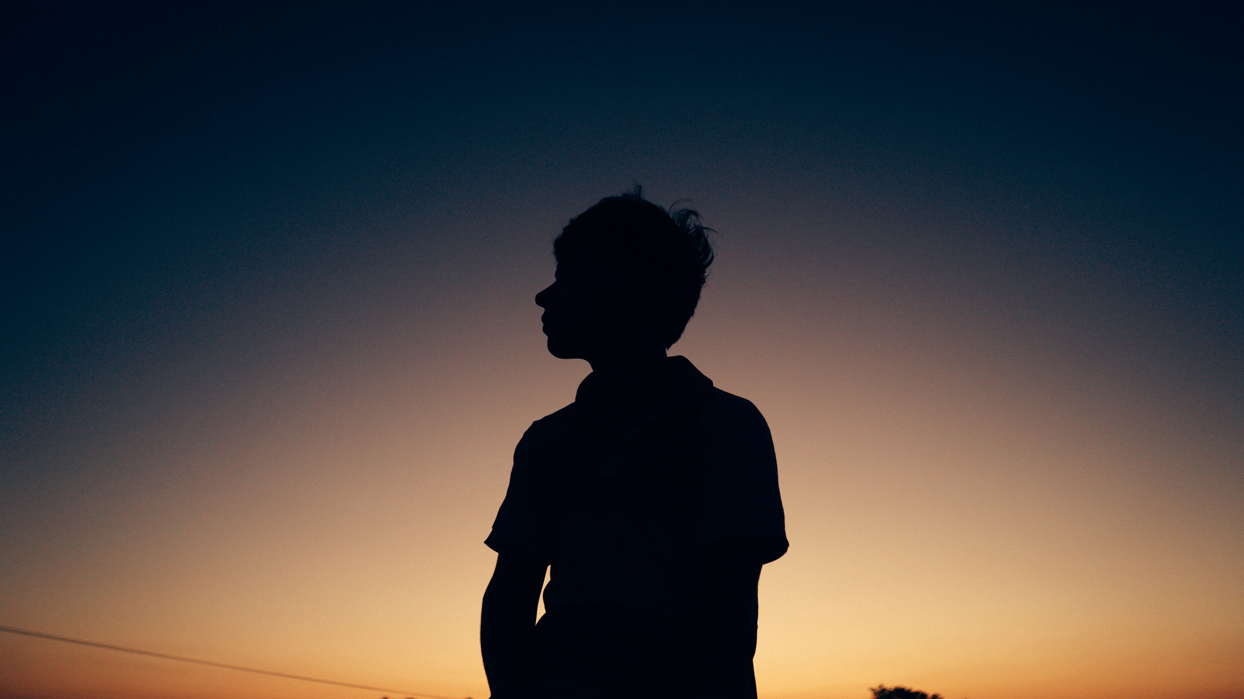 a silhouette of a person standing in front of a sunset