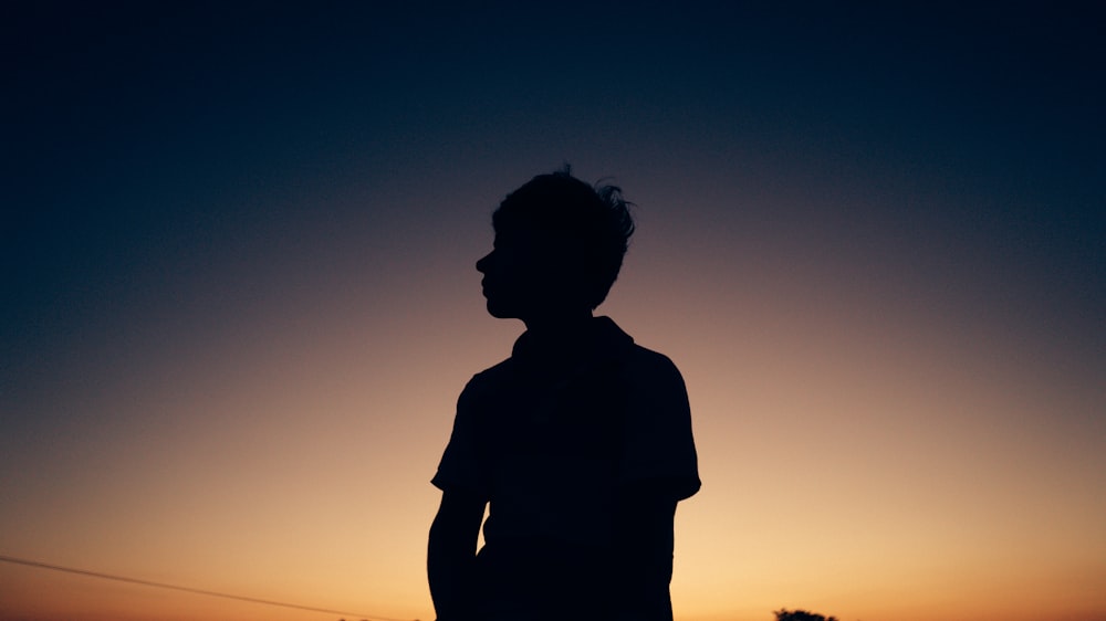 a silhouette of a person standing in front of a sunset