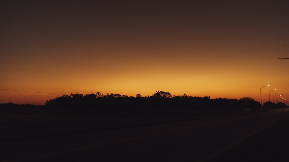 the sun is setting over the horizon of a highway