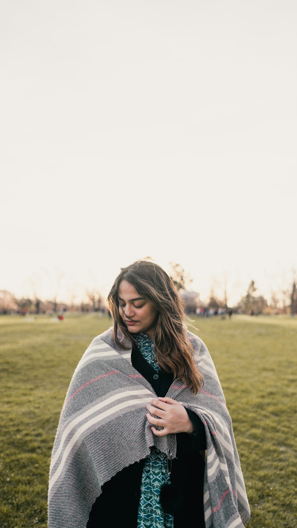 a woman wrapped in a blanket in a field