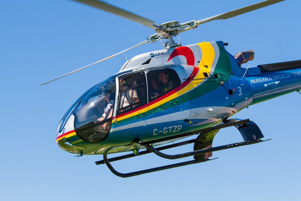 a colorful helicopter flying through a blue sky